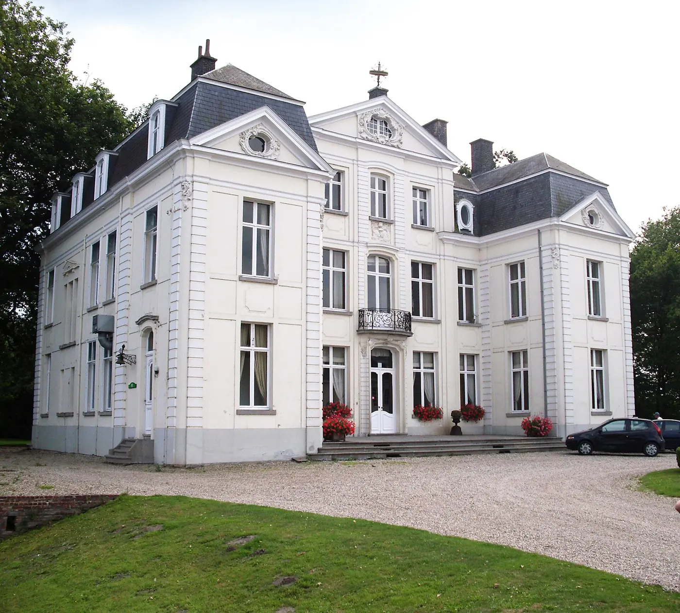 Het witte neoclassicistische Kasteel van Wippelgem in Evergem met een leien mansardedak en een grindpad ervoor.