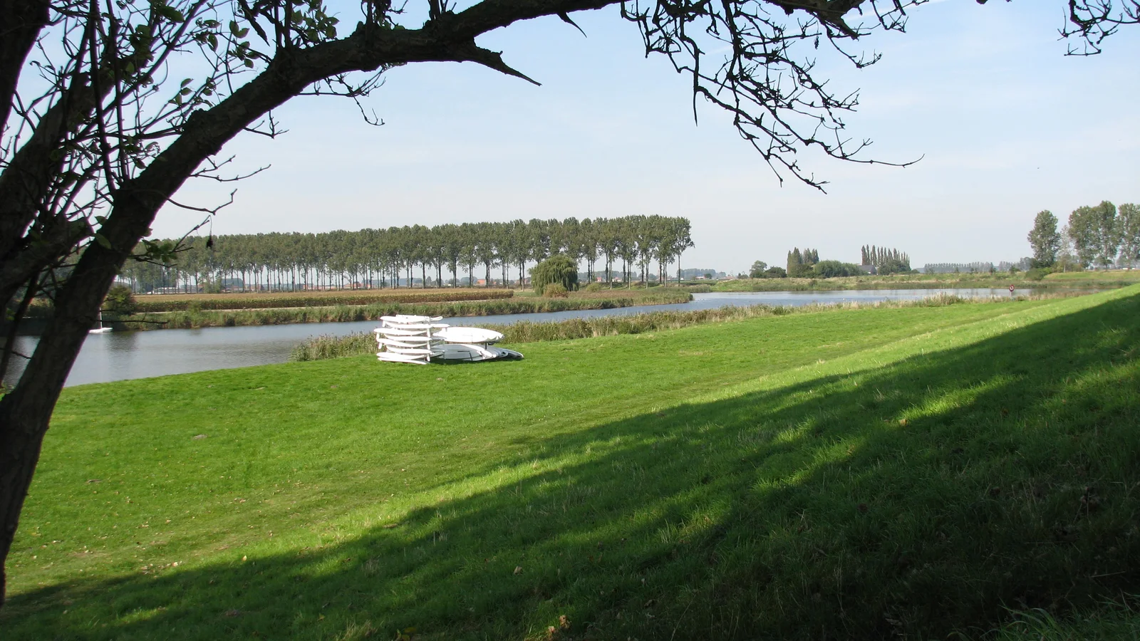 Landschapszicht over de Boerenkreek in Sint-Laureins, typisch krekenlandschap van het Meetjesland met riet en open water.